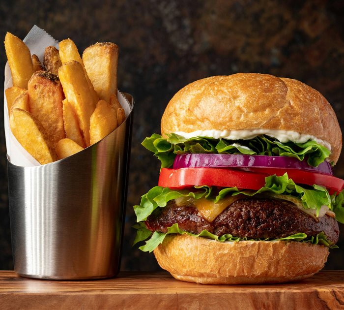 Cheeseburger with lettuce, tomato, onion and French fries in metal container
