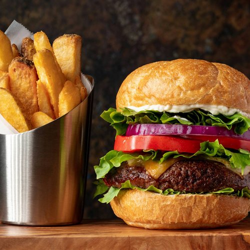 Cheeseburger with lettuce, tomato, onion and French fries in metal container