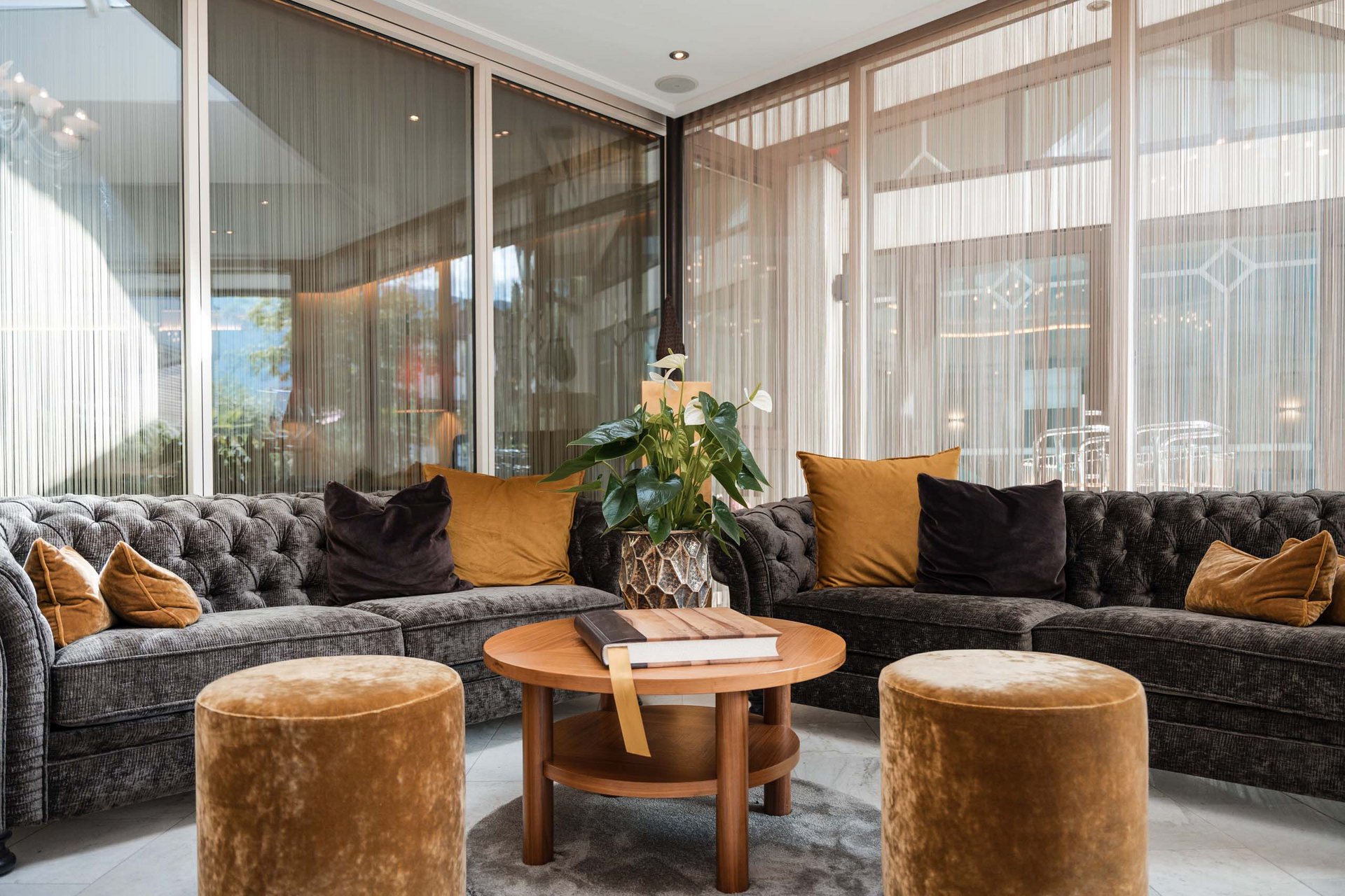 Moderne gemütliche Sitzecke mit zwei Sofas, Hockern und runden Holztisch