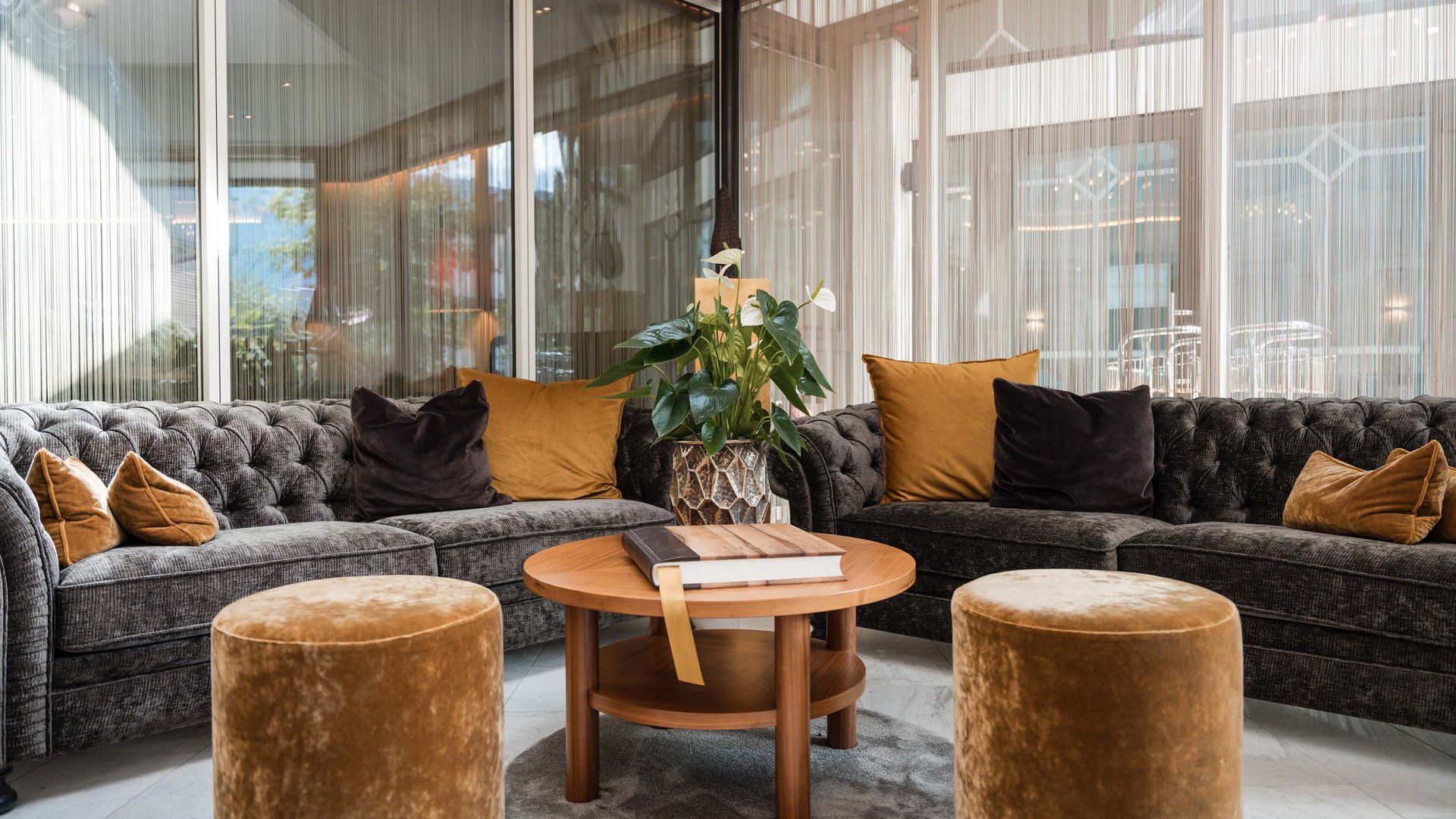 Moderne gemütliche Sitzecke mit zwei Sofas, Hockern und runden Holztisch