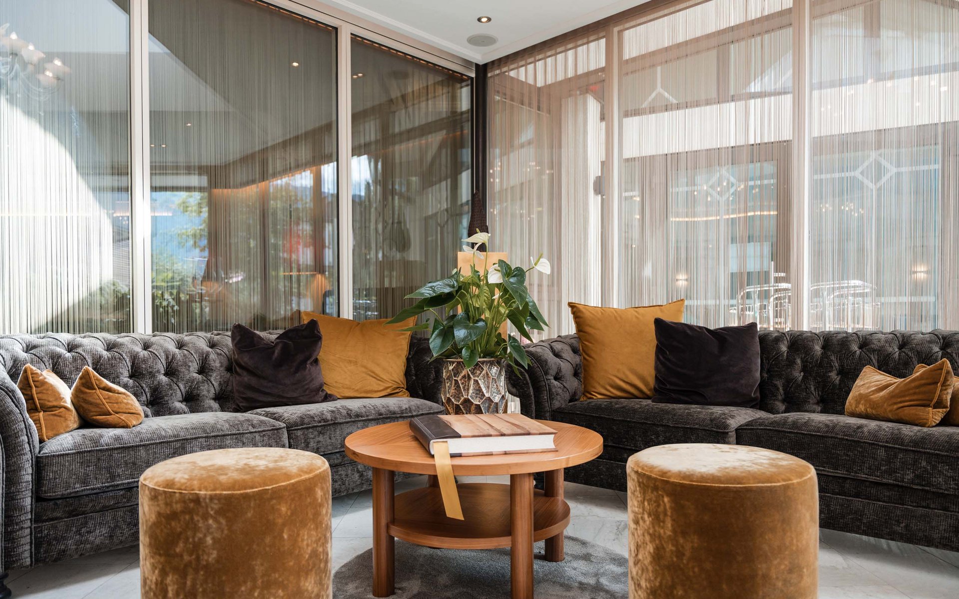 Moderne gemütliche Sitzecke mit zwei Sofas, Hockern und runden Holztisch
