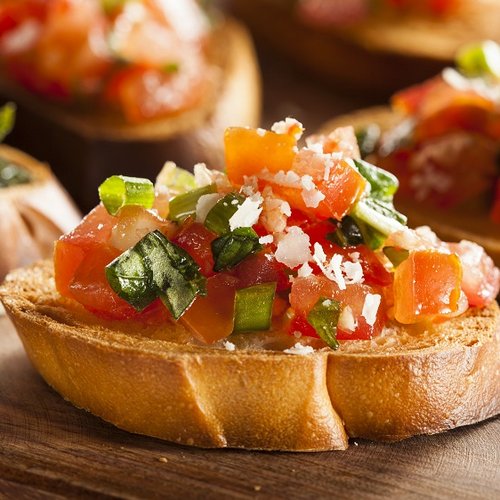 Bruschetta with tomatoes, basil, and parmesan on wooden cutting board