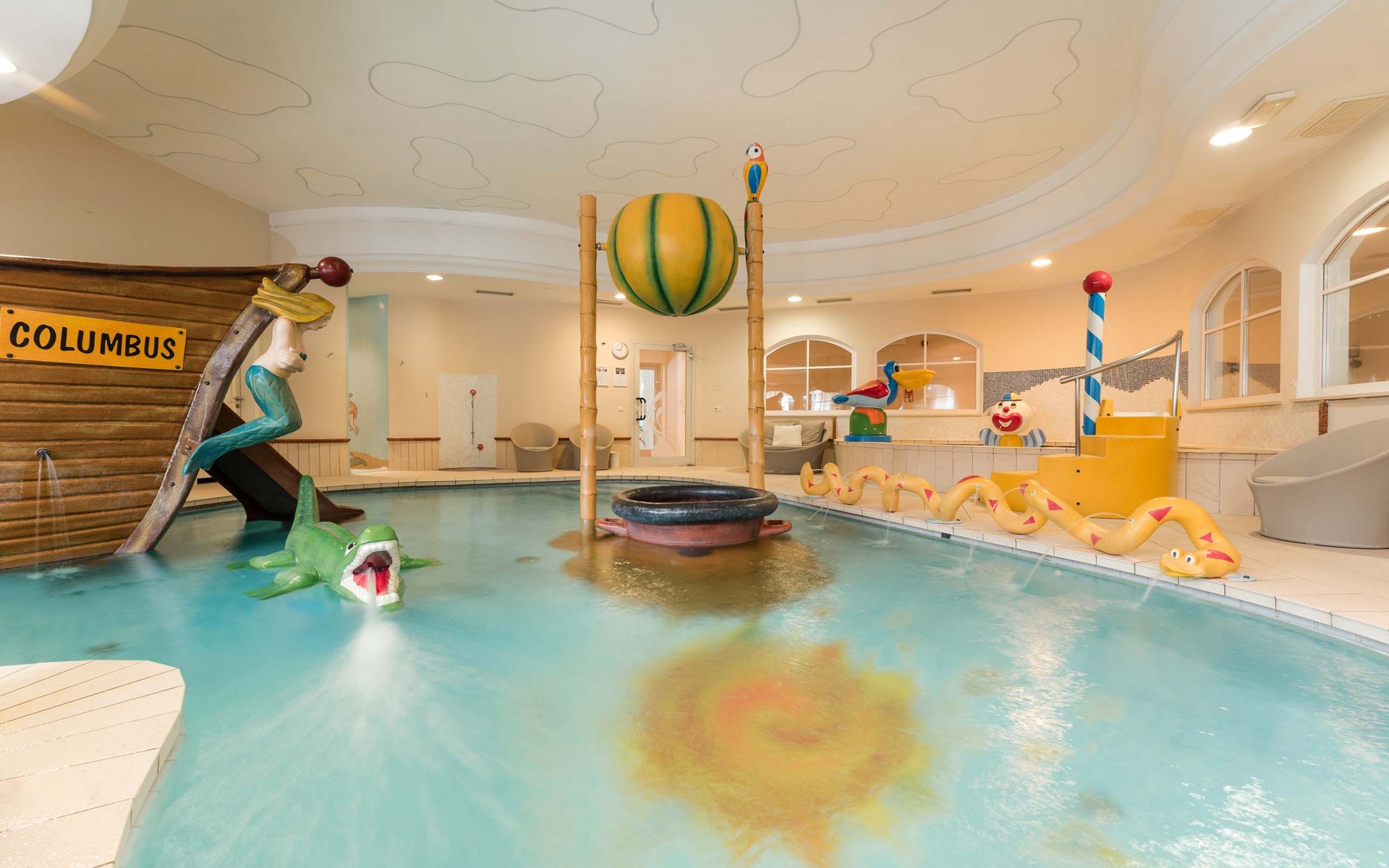 Innenkinderpool mit Bootsrutsche und Wasserspielzeug in gelbem Raum