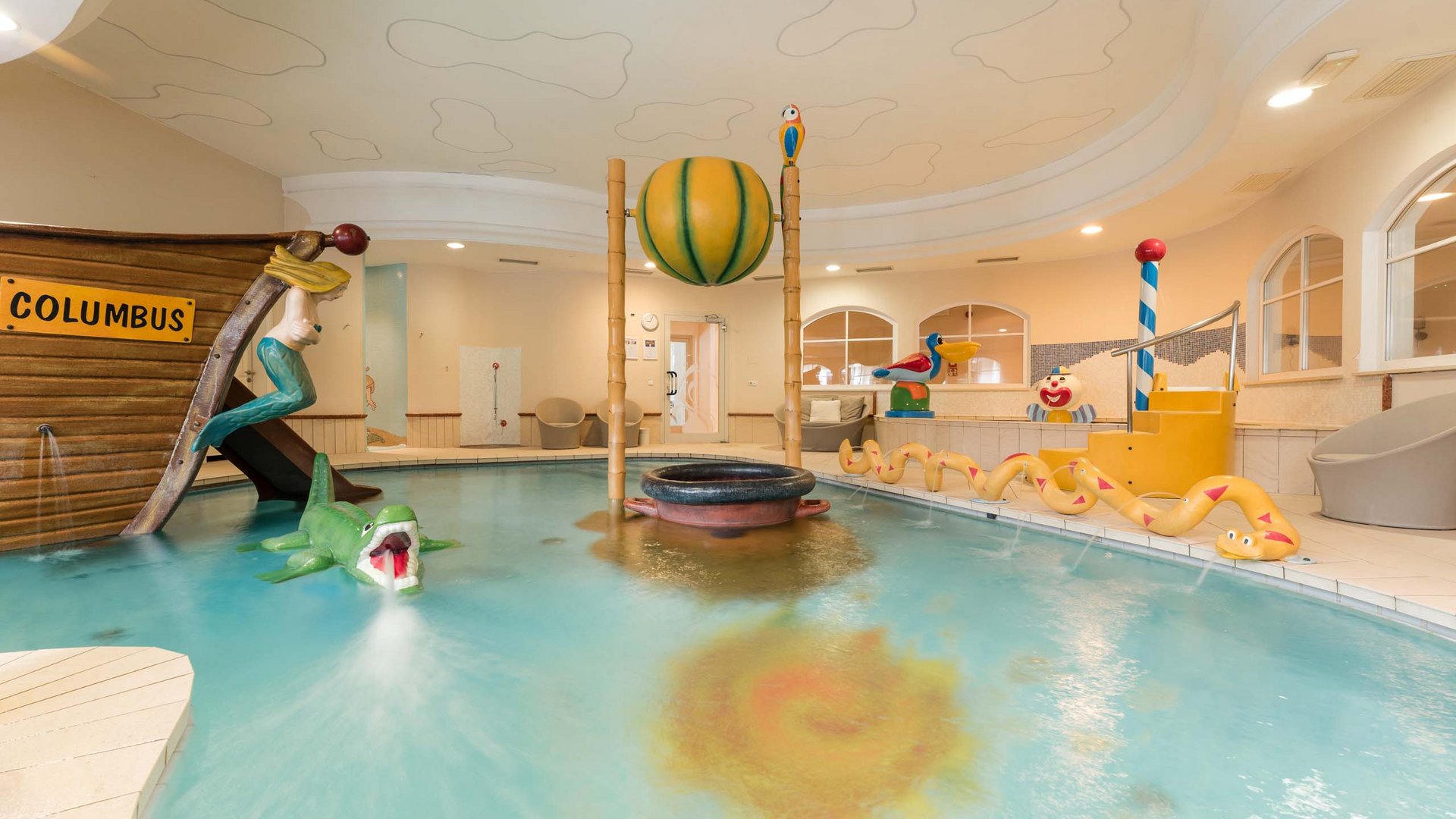 Innenkinderpool mit Bootsrutsche und Wasserspielzeug in gelbem Raum