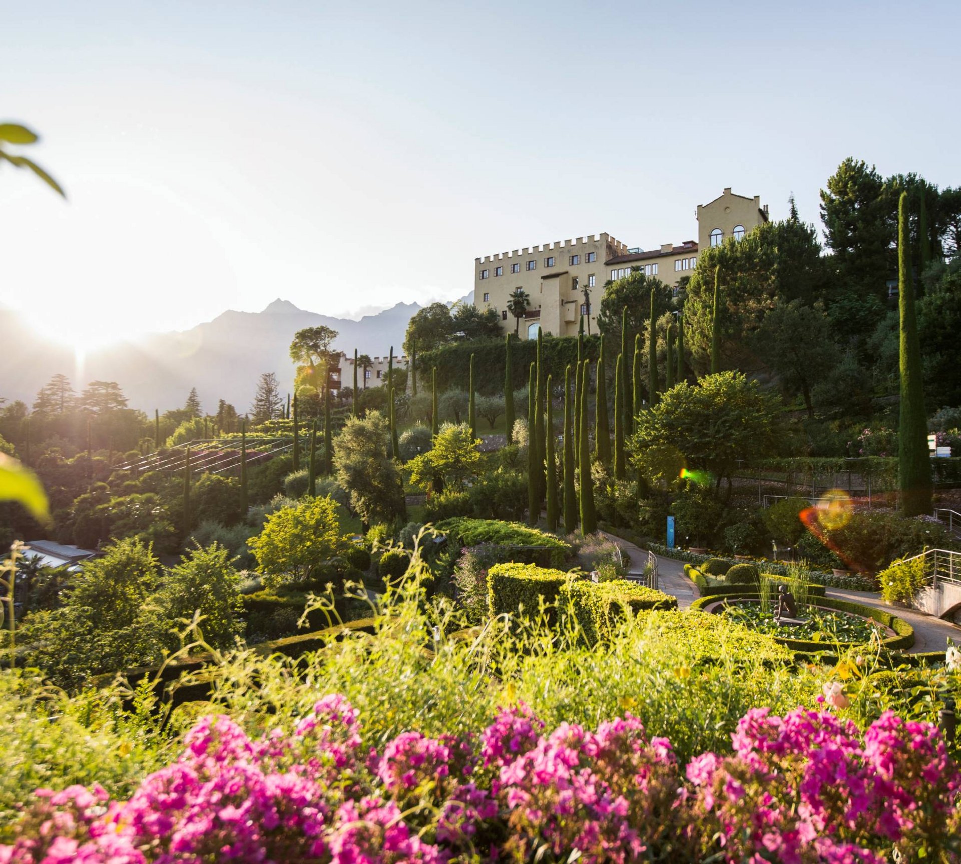Schloss mit Garten, hohen Zypressen und Sonnenuntergang in den Bergen