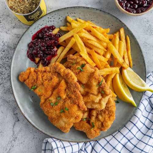 Breaded schnitzel with fries, lemon wedges, and lingonberry sauce on a plate