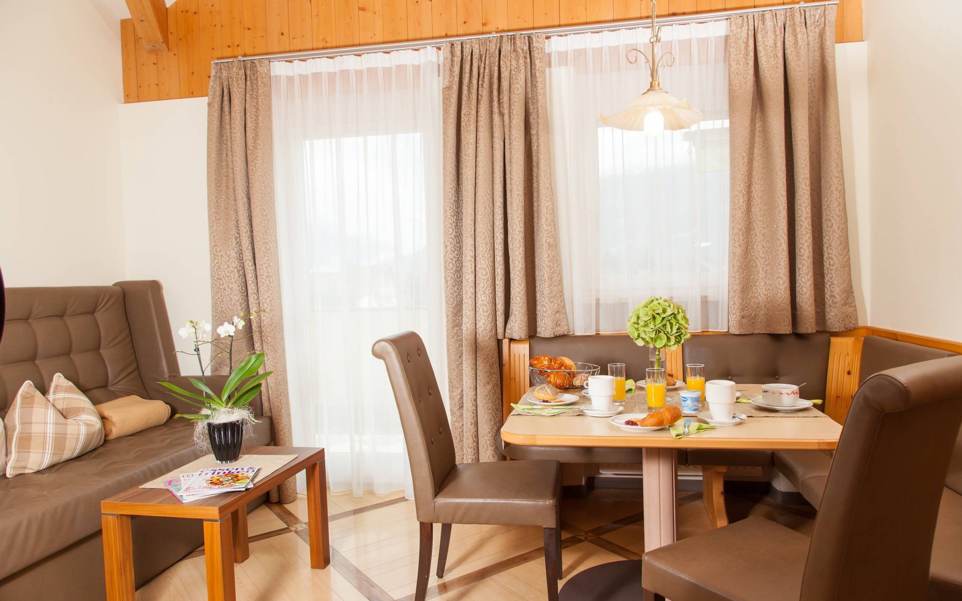 Gemütlicher Essbereich mit Speisetisch, Stühlen und Sofa in warmen Tönen