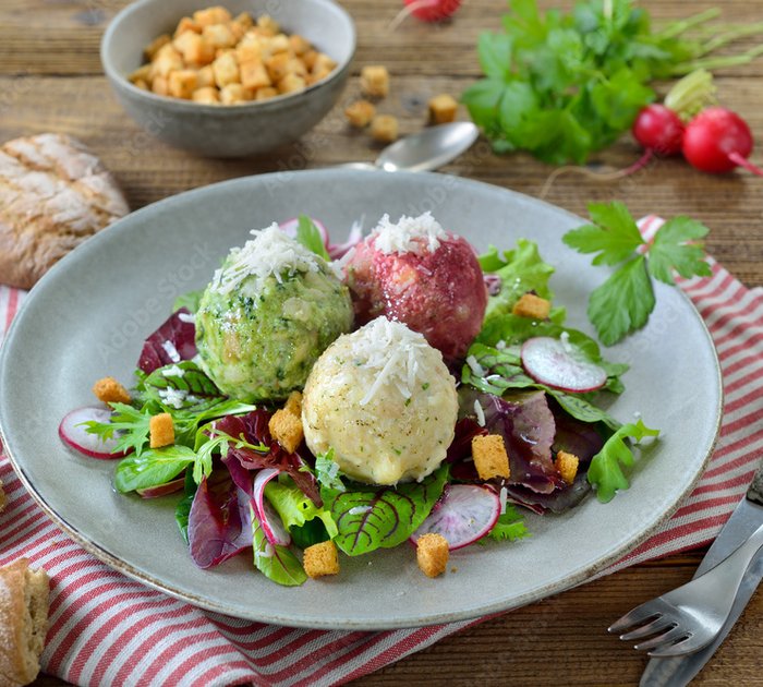 Three colorful dumplings on mixed leaf salad with croutons on plate