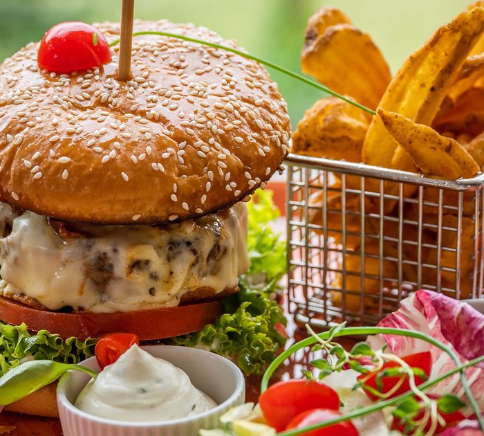 Cheeseburger with lettuce, fries and sauces on a plate