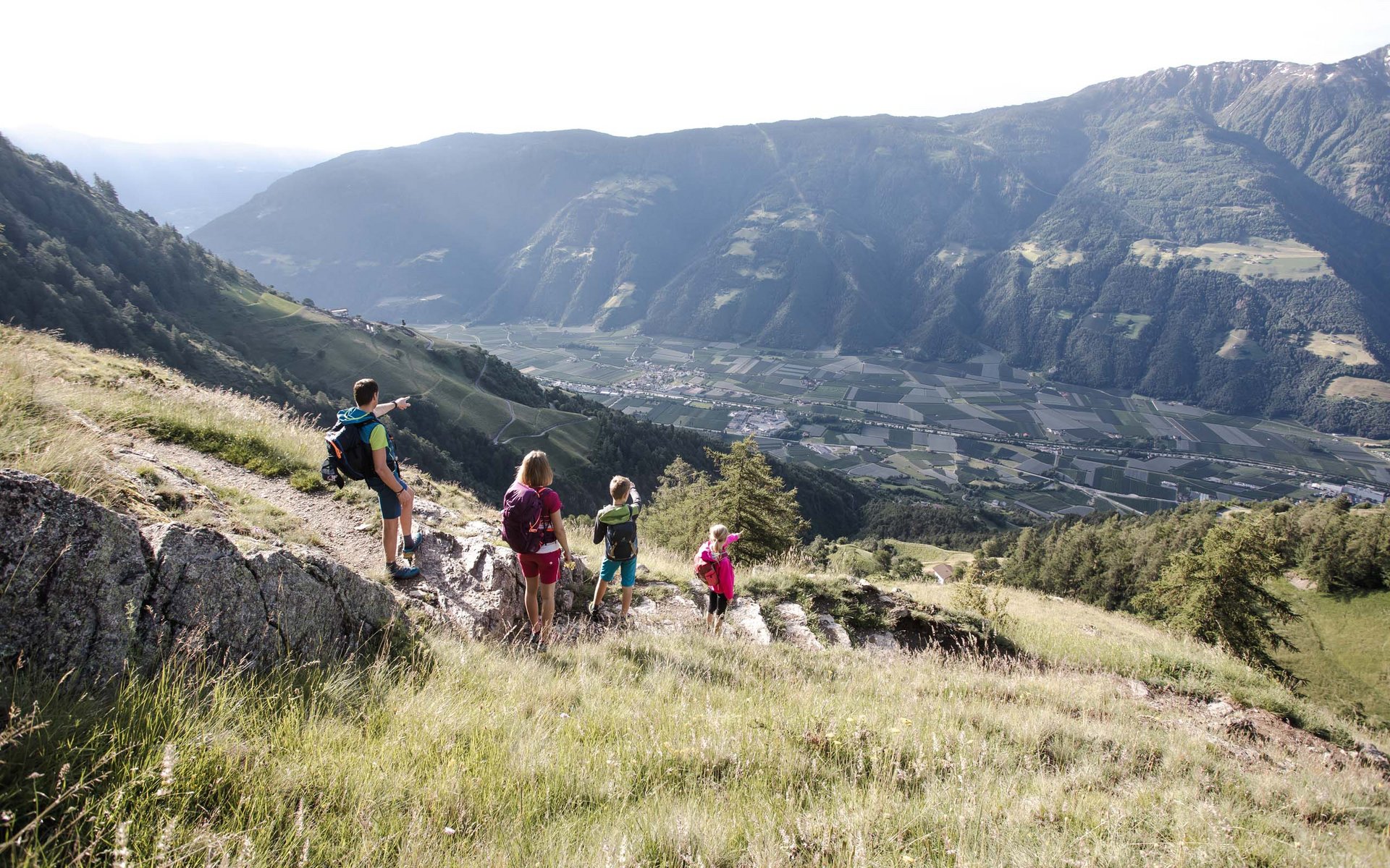 Familie wandert auf Bergweg mit Blick auf Tal und Berge