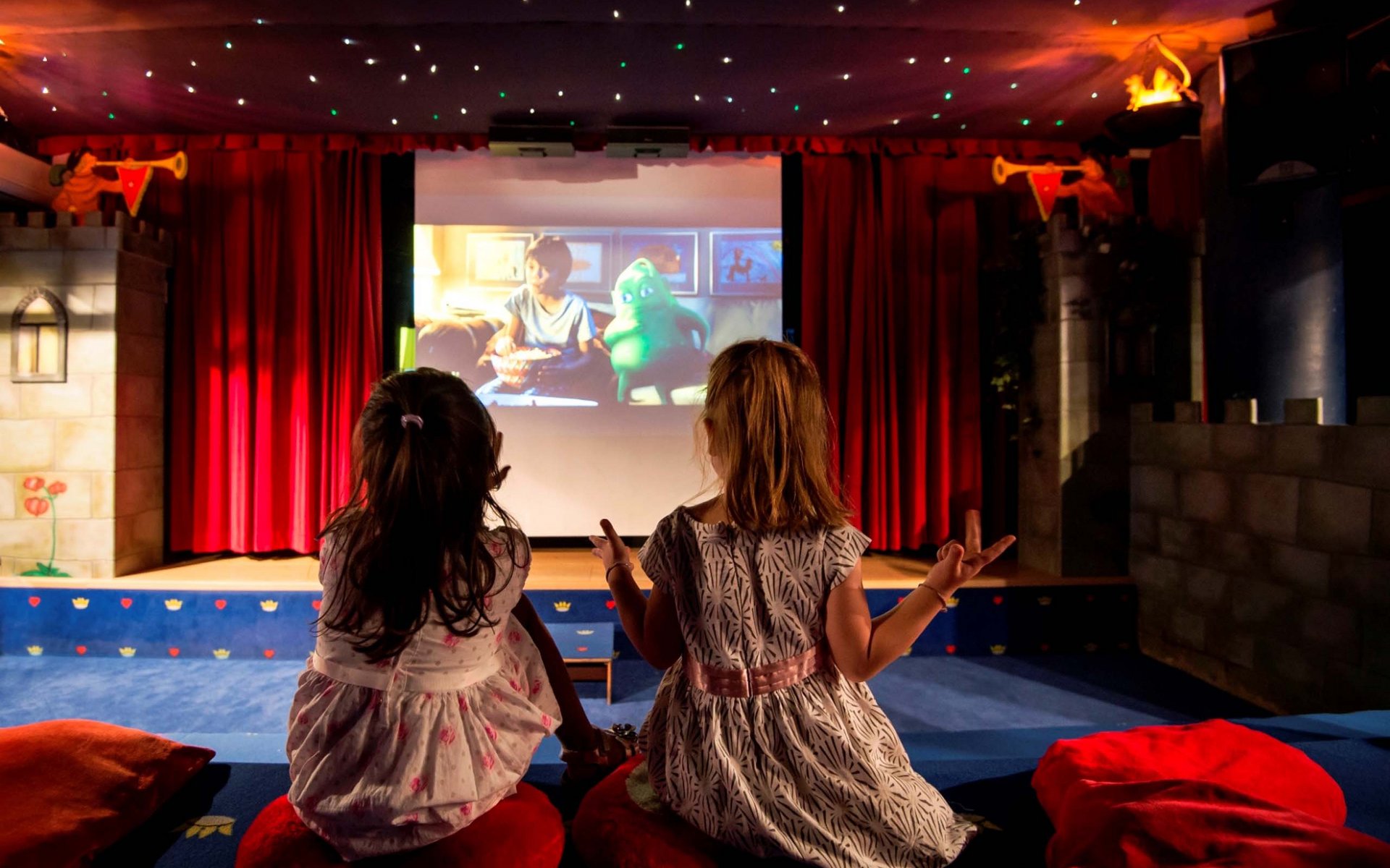 Zwei Mädchen schauen einen Animationsfilm in einem kinderfreundlichen, bunten Kino