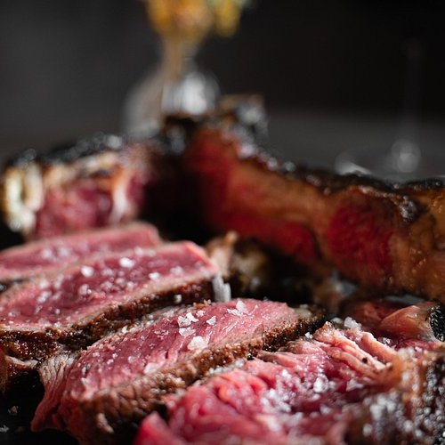 Close-up of sliced pink, juicy steak on a dark plate