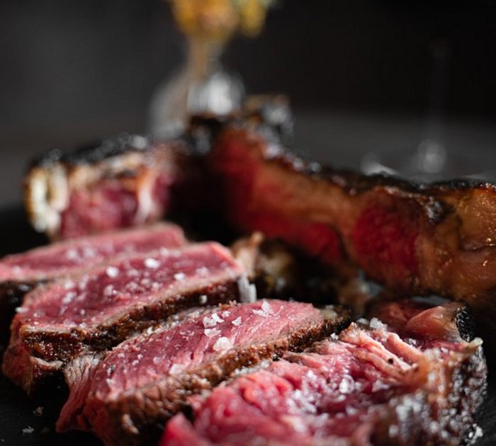 Close-up of sliced pink, juicy steak on a dark plate
