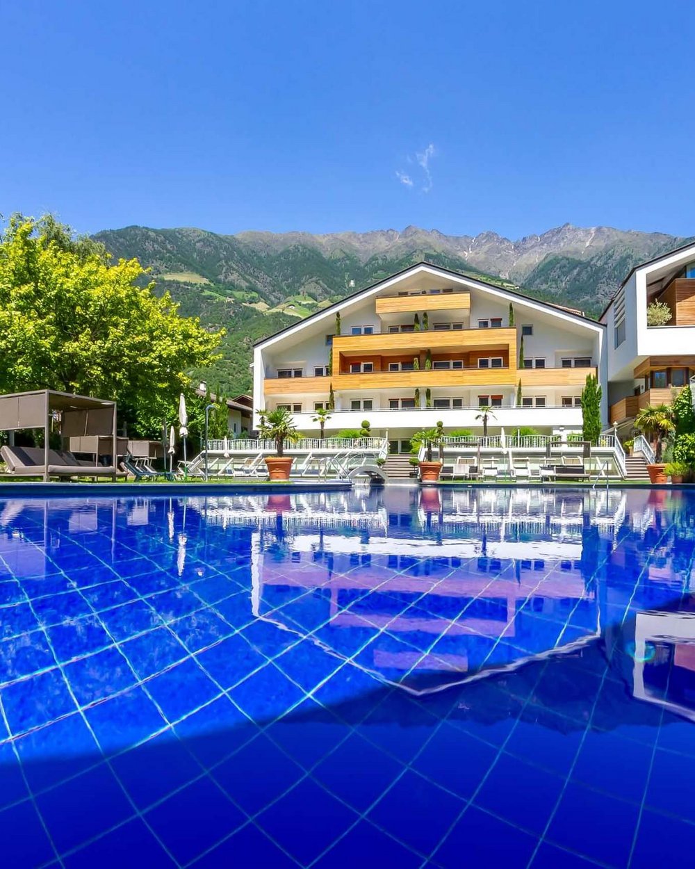 Piscina con acqua blu davanti a un moderno hotel in montagna