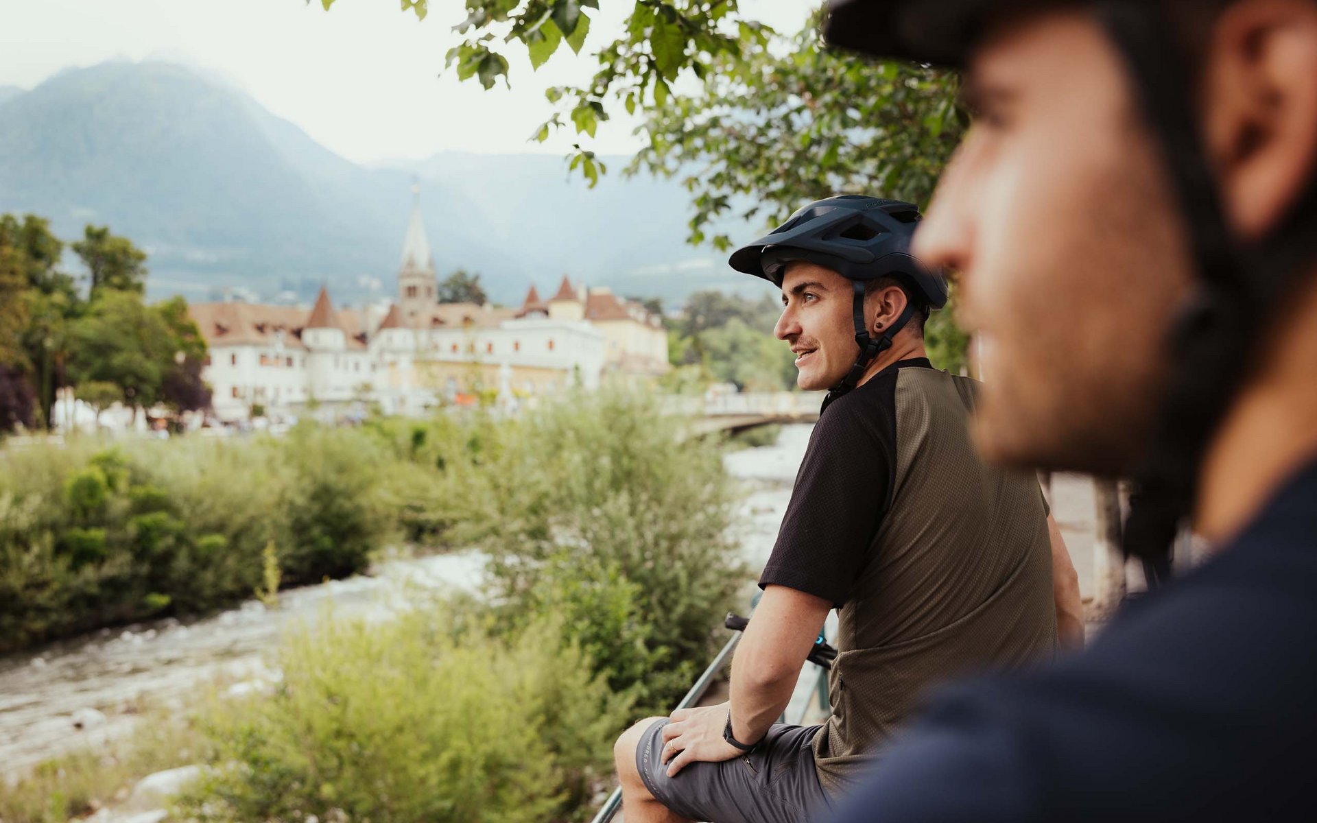 Zwei Radfahrer mit Helmen genießen Aussicht auf Fluss und historische Stadt