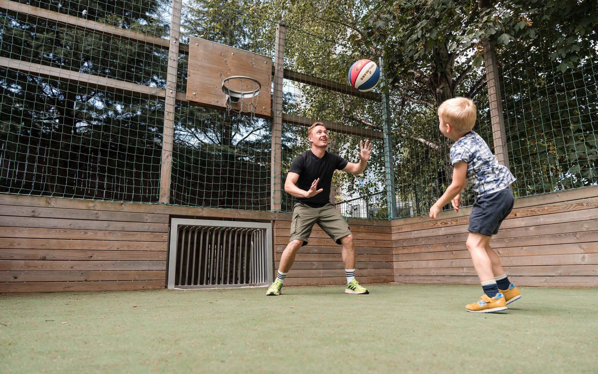 Vater und Sohn spielen Basketball auf einem kleinen Outdoor-Feld