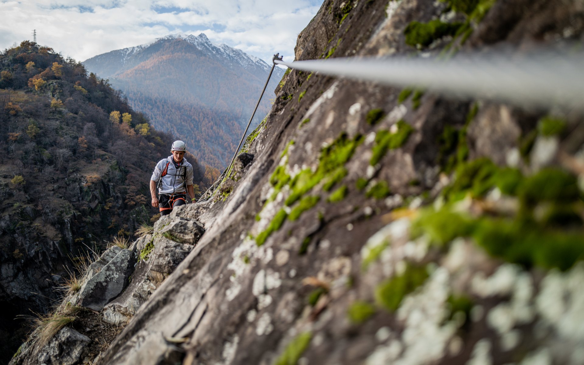 Kletterer am gesicherten Felsen mit Berg im Hintergrund