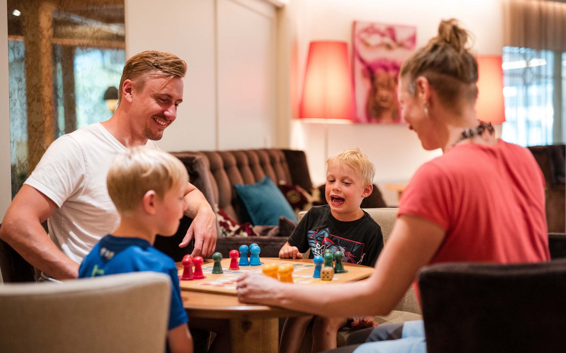 Familie spielt Brettspiel gemeinsam am Tisch im Wohnzimmer