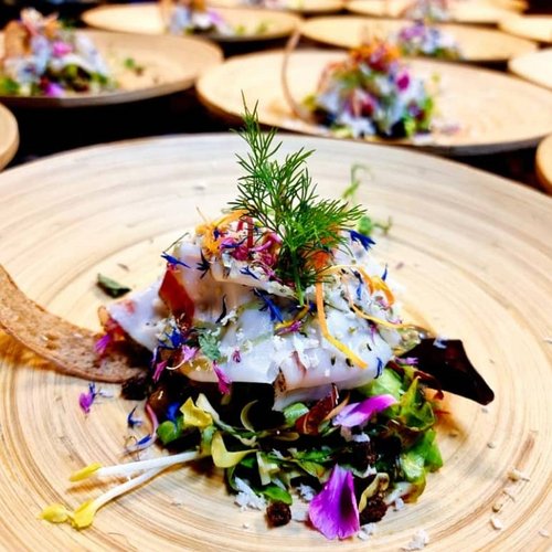 Artistically plated salad with edible flowers on a wooden plate