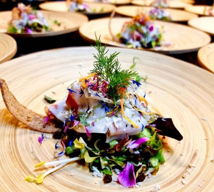 Artistically plated salad with edible flowers on a wooden plate