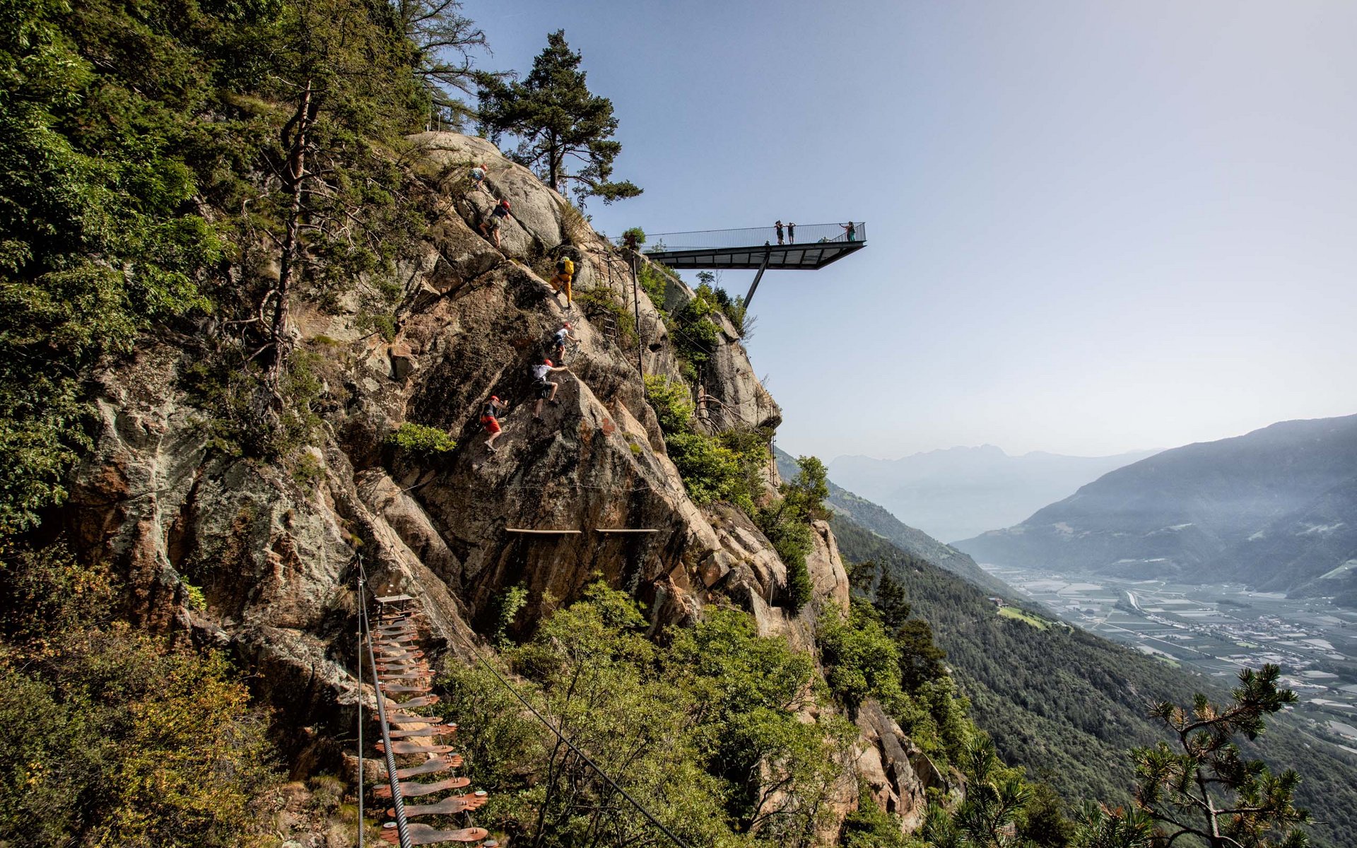 Kletterer steigen an Felsen mit Aussichtspunkt und Talblick