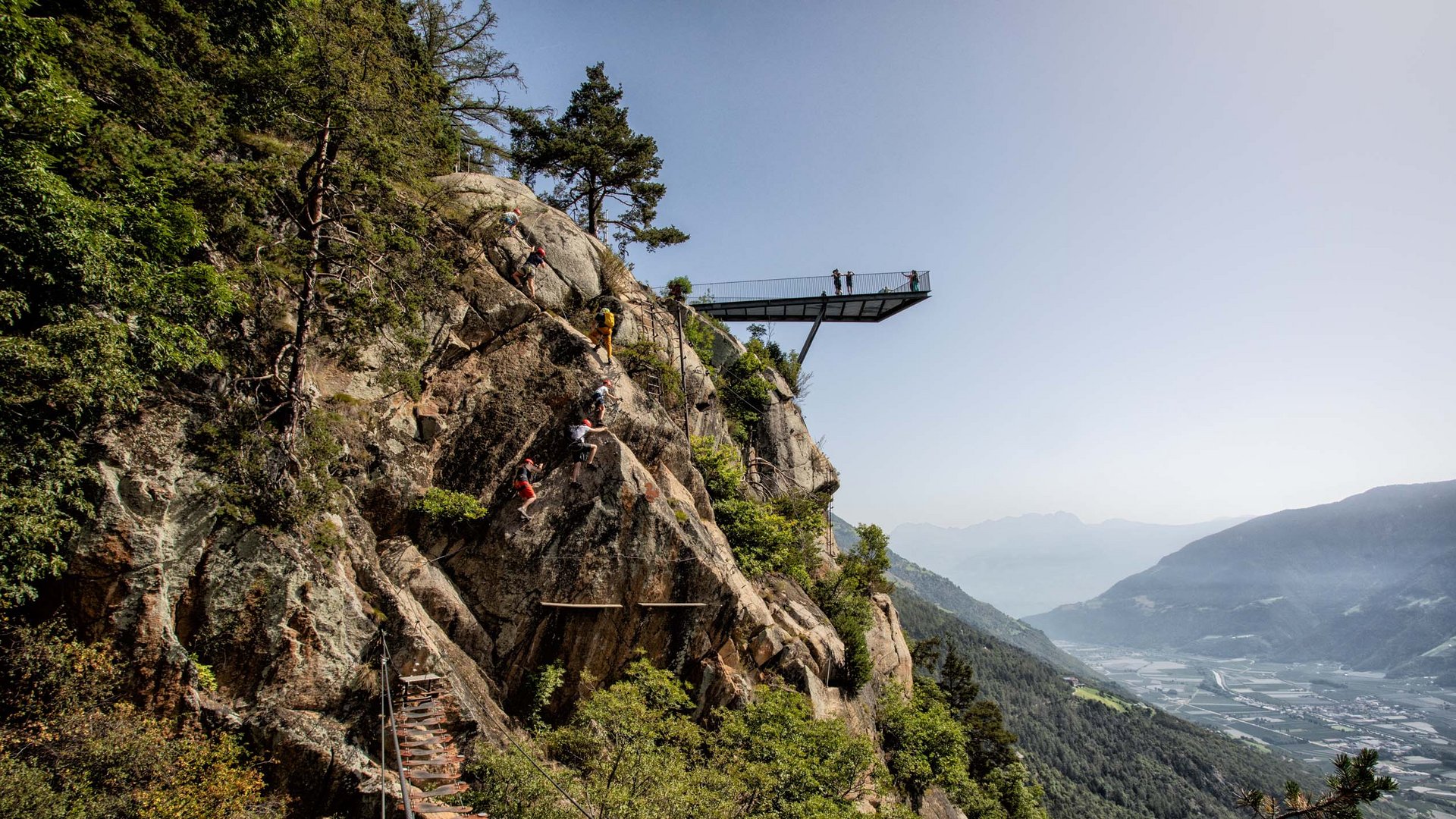 Kletterer steigen an Felsen mit Aussichtspunkt und Talblick