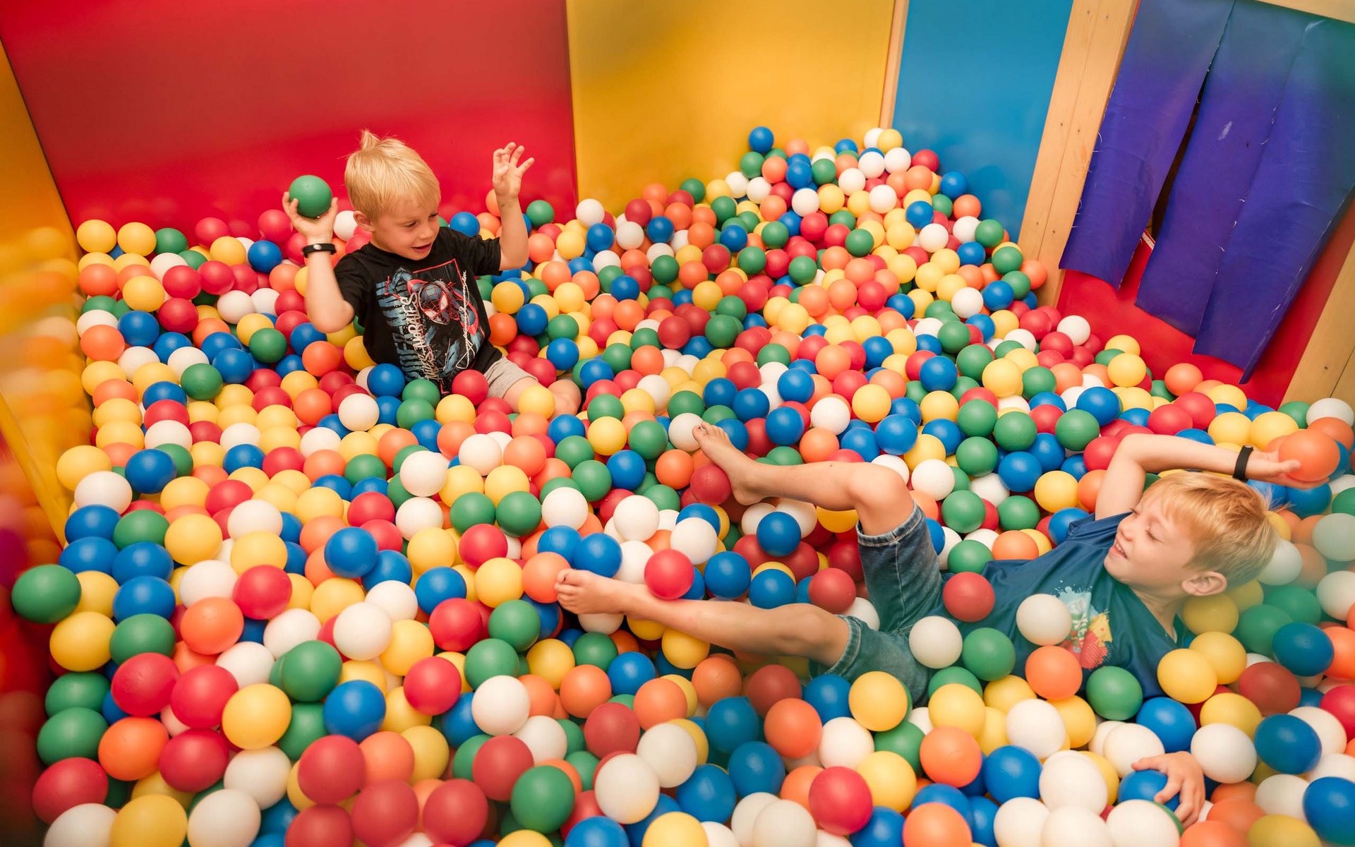 Zwei Jungen spielen in einem Bällebad mit bunten Kunststoffbällen