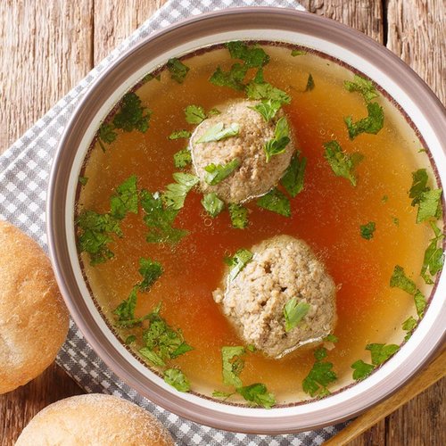 Clear meat broth with two meatballs and fresh parsley