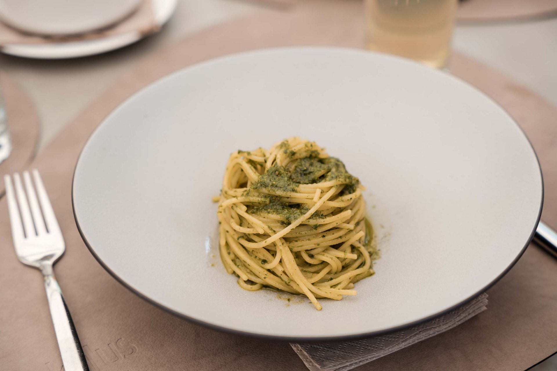 Spaghetti with green pesto sauce on a white plate