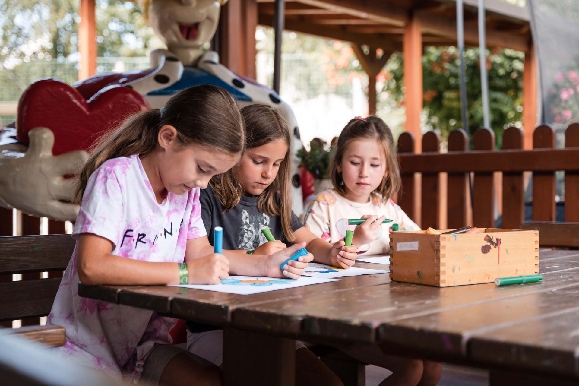 TYROL Family Retreat: eines der besten Kinderhotels Europas Drei Mädchen sitzen am Tisch und malen mit Stiften auf Papier