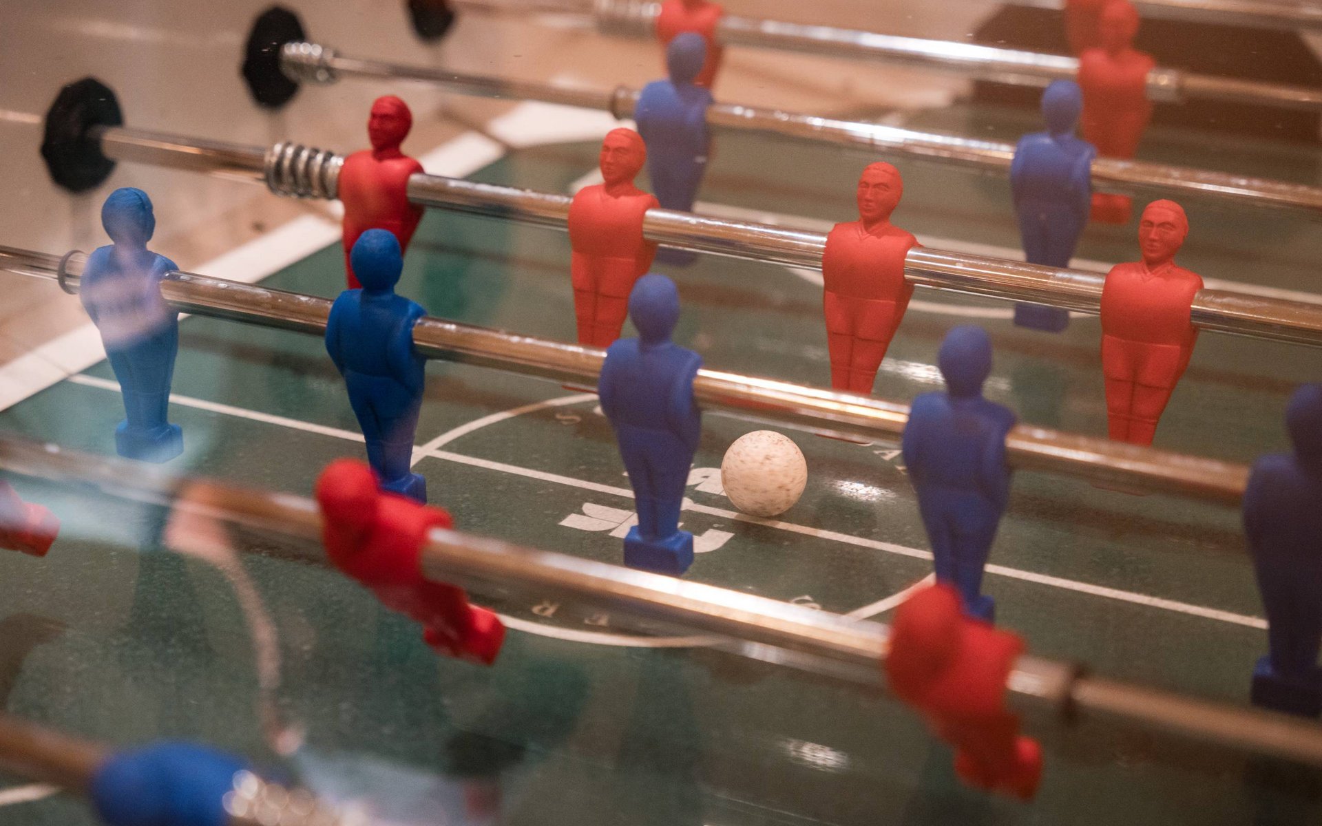 Tischfußballspiel mit roten und blauen Figuren und weißem Ball