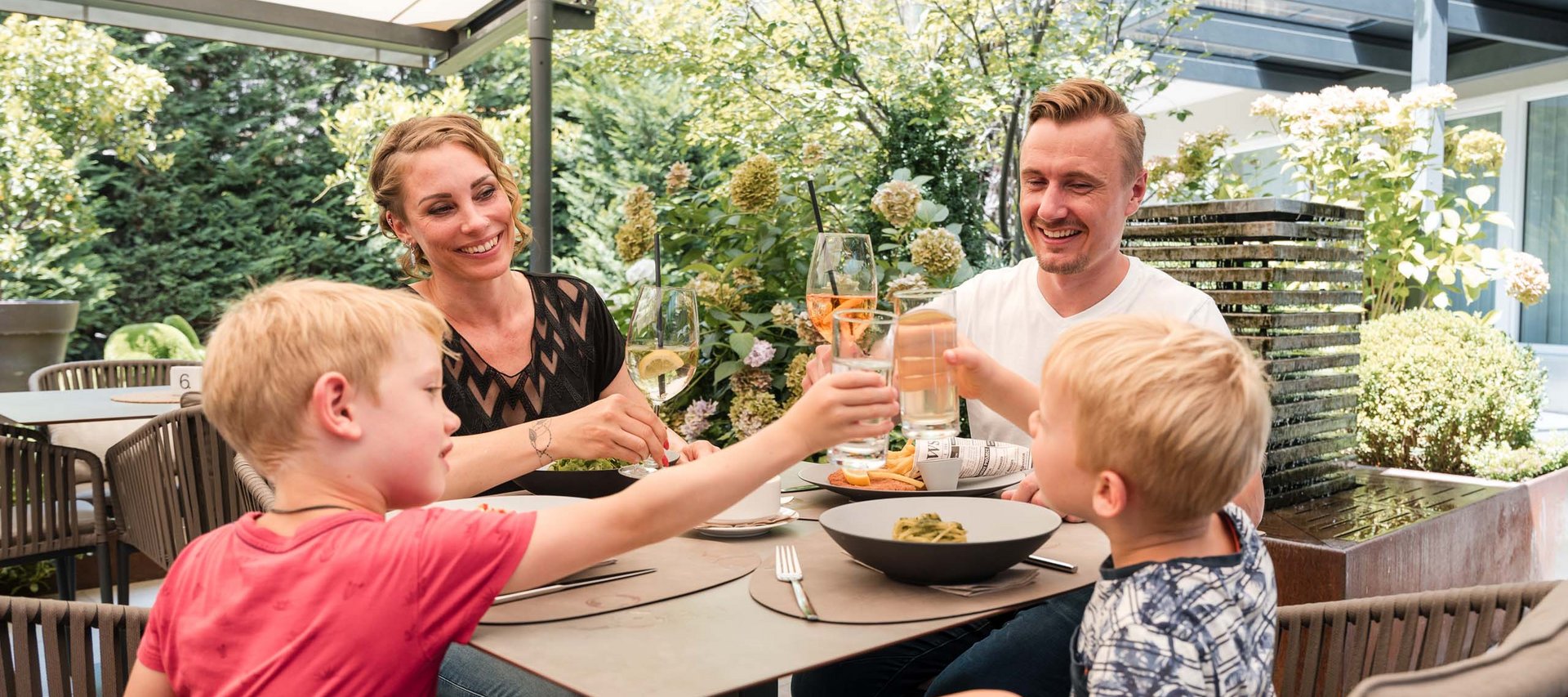 Family cheers with drinks while dining together in garden