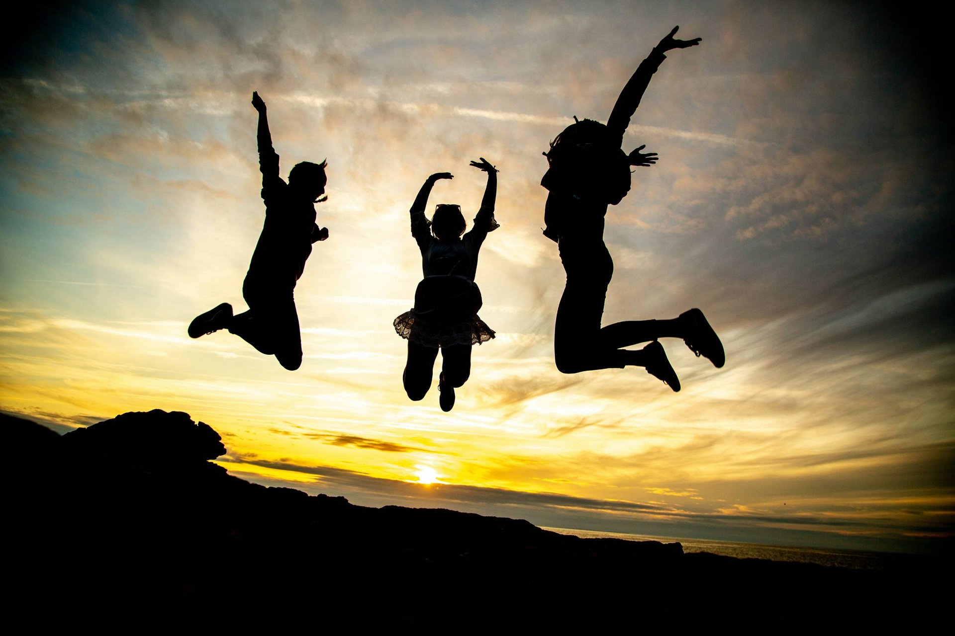 Tre persone saltano silhouette contro il tramonto