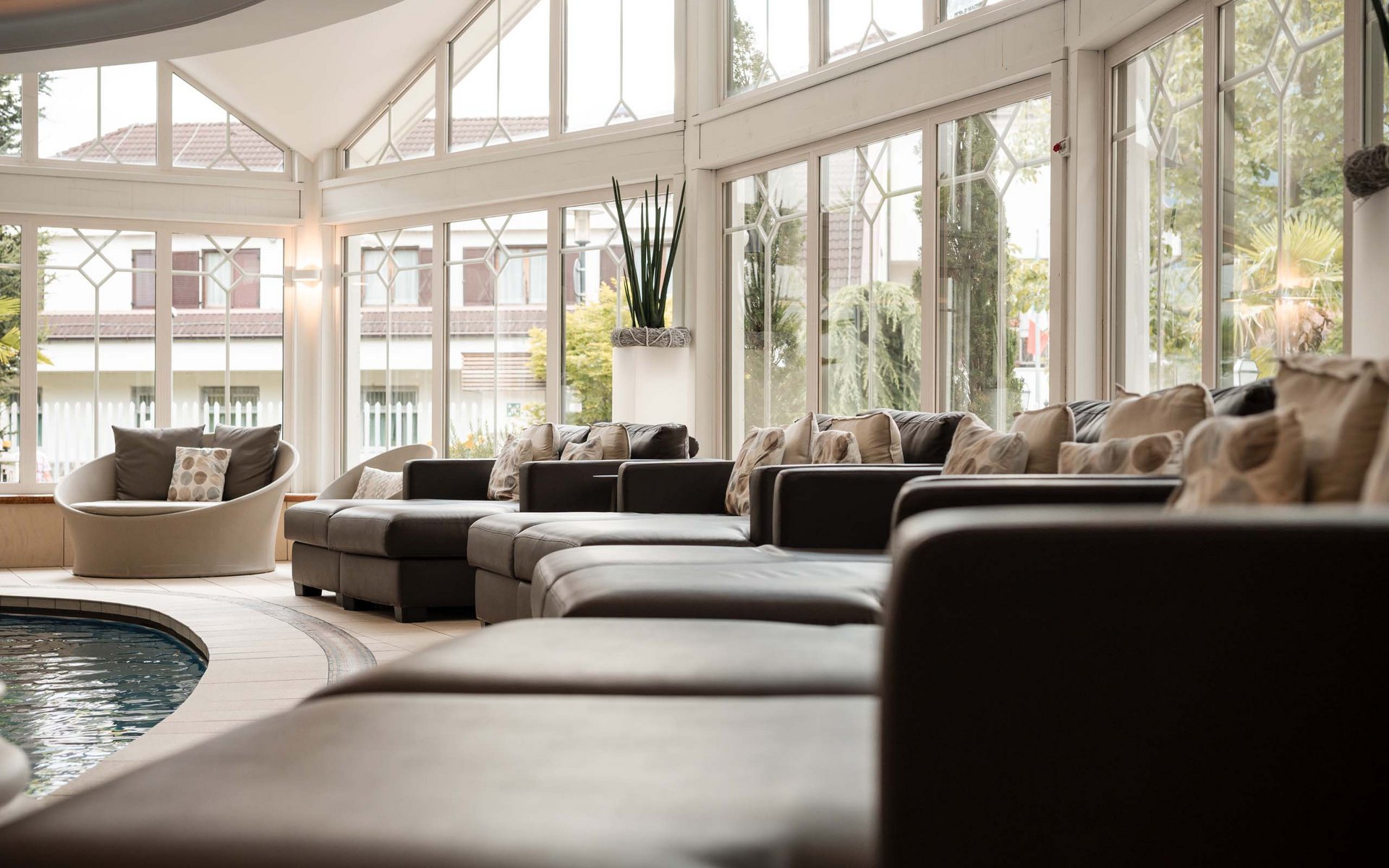 Helle Lounge mit Ledersofas und großen Fenstern am Innenpool