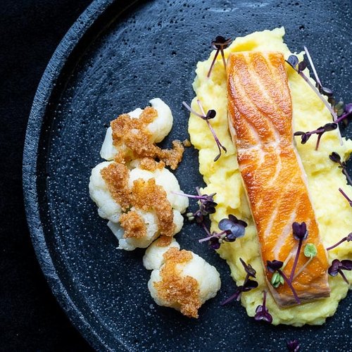 Grilled salmon fillet on mashed potatoes with cauliflower and microgreens