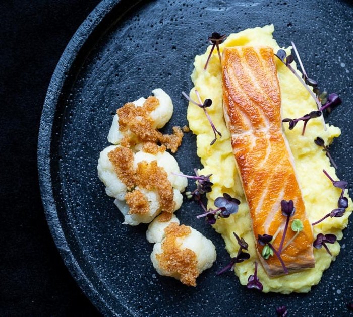 Grilled salmon fillet on mashed potatoes with cauliflower and microgreens