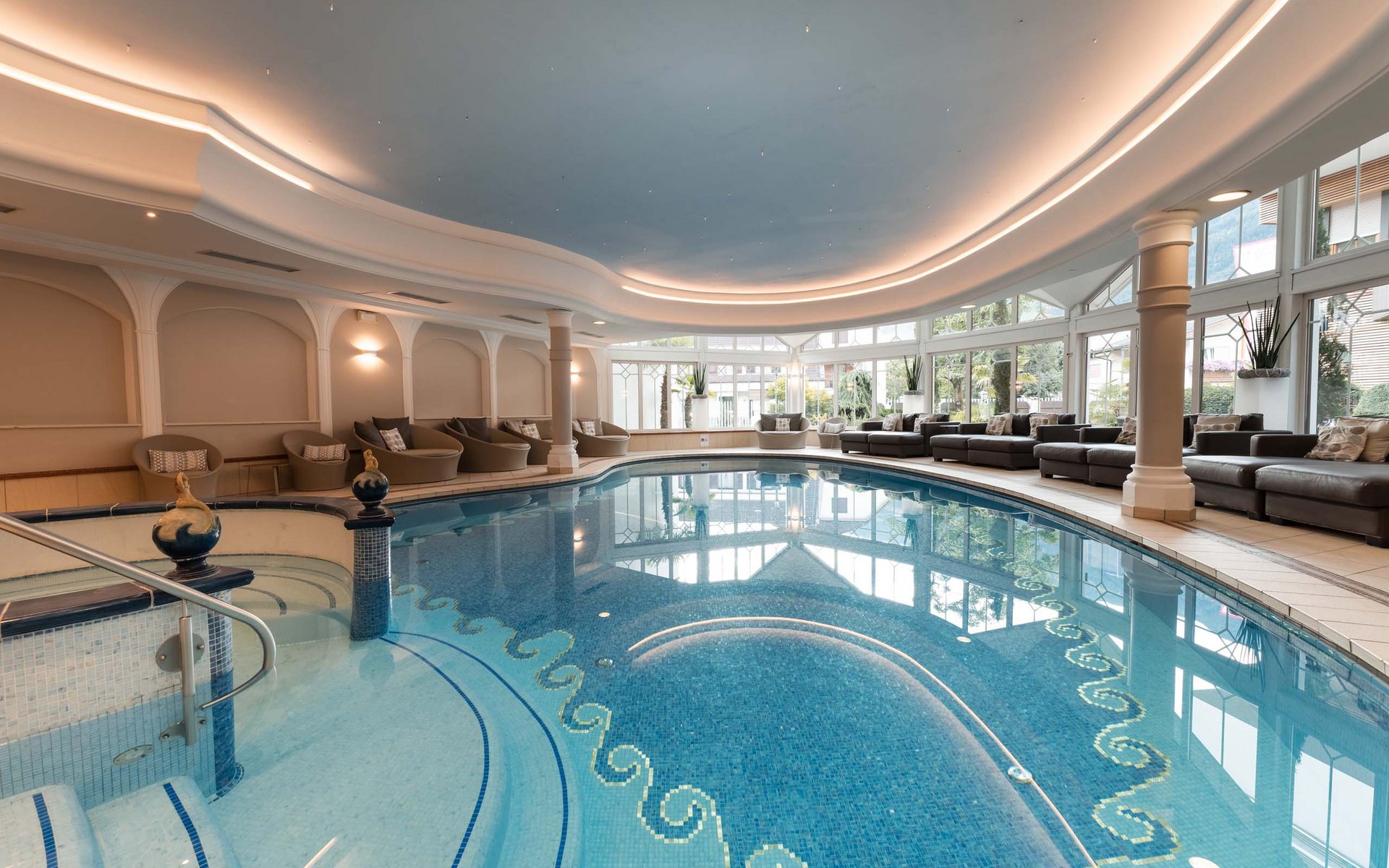 Hallenbad mit Lounge-Bereich und großen Fenstern mit Blick ins Freie