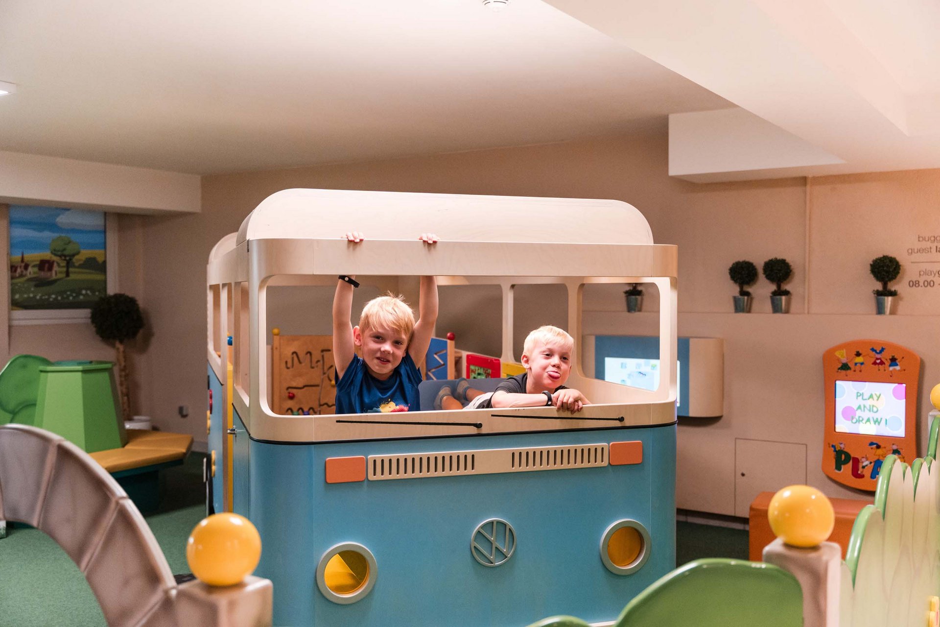 Zwei Kinder spielen in einem blauen Spielbus im Innenbereich